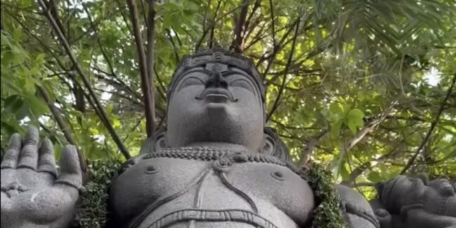 Garlanded stone deity statue beneath tree canopy at Sri Narayani Peedam, Vellore, Tamil Nadu