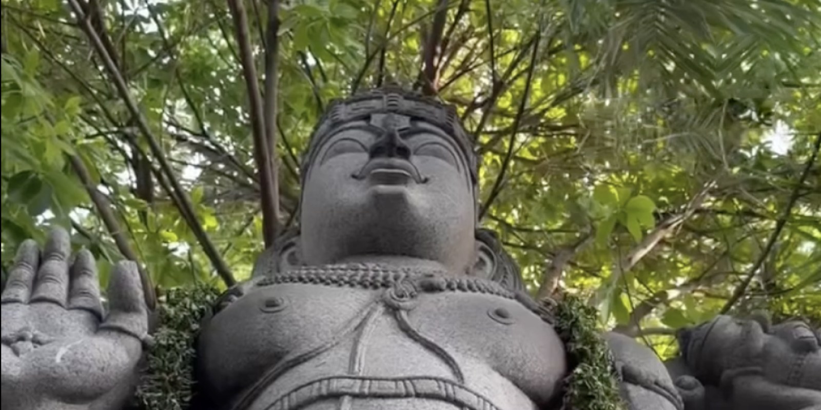 Garlanded stone deity statue beneath tree canopy at Sri Narayani Peedam, Vellore, Tamil Nadu